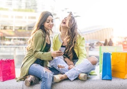 Female friends watching something funny on a smartphone - Girlfriends laughing and having fun outdoors