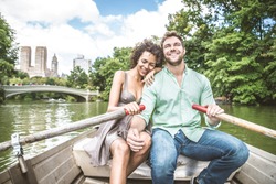 Happy couple having fun on a boat in Central Park - Interracial couple of tourists sightseeing Manhattan