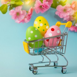 Colorful painted Easter eggs in shopping cart on blue background. Sale. Shopping