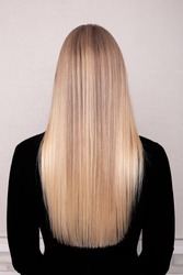 
Female back with long blonde healthy hair in hairdressing salon