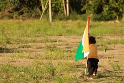 Bhadrak, Odisha, India: Adorable Cute little Indian Children Proudly holding the Tricolour Indian flag with greenery in the background, celebrating Independence or Republic day.
