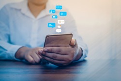 Person using a social media marketing concept on mobile phone with notification icons of like, message, comment and star above smartphone screen.