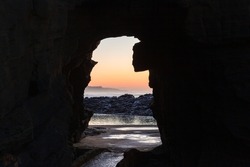 Beach rocky coastline walking path through cliff hole to tidal pool  morning dawn landscape.