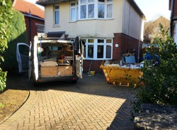 Self employed builder van with building tools & yellow skip full of rubbish situated near the house. Photo for background use as home renovation, investment project. Space to add text on driveway.