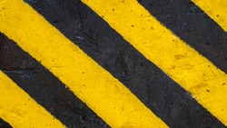 Yellow and black strip paint on road surface; asphalt road texture sign