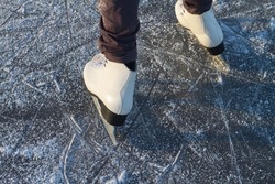 To skate on the ice of a river or lake in winter, white skates slide on the ice in close-up.