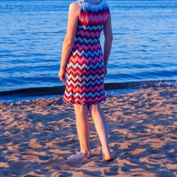 A woman in a red and blue knitted dress with a Missoni zigzag pattern on the beach in summer