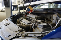 Car in service with an open hood. In the photo, the top of the engine, the battery. Service, repair, spare parts for a modern car. Concept.