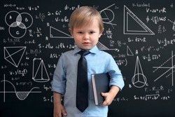 a smart boy in a school uniform, standing at the blackboard with mathematical signs, graphs and formulas. Smart, brilliant children. The concept of education