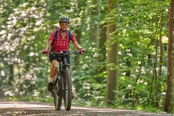 nice active senior woman riding her electric mountain bike in the green city forest of Stuttgart, Germany