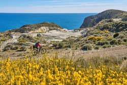 nice senior woman cycling with her electric mountain bike in the volcanic nature park of Cabo de Gata, Costa del Sol, Andalucia