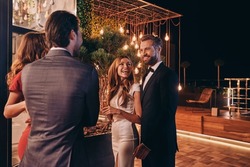 Group of people in formalwear communicating and smiling while spending time on luxury party