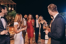 Group of beautiful people in formalwear communicating and smiling while spending time on luxury party