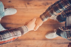 Men shaking hands. Top view of two men shaking hands while standing on the wooden floor