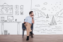 Your dreams can send you far away. Young handsome man keeping hand on chin and looking away while sitting in the chair against illustration of fjord vs. working place