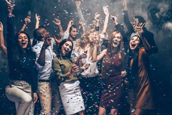 Party fun. Group of beautiful young people throwing colorful confetti and looking happy