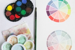 watercolor color discs on white table, with fabric and watercolor paint brush, chromatic disk watercolor