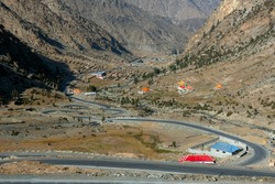 beautiful zigzag road in the mountains with red huts and green valley 