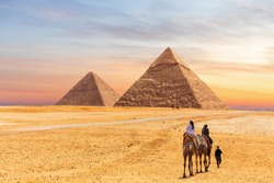 Pyramids of Giza and the tourists on a camel, Egypt
