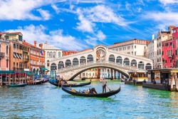 Famous buildings, gondolas and monuments by the Rialto Bridge of Venice on the Grand Canal, Italy