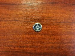 Silver Lens door soft focus at center of brown wooden door. Installing on wood texture background
