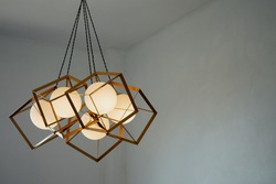 A round lamp with a rectangular iron frame suspended from the ceiling, illuminating in gold. Interior concept.