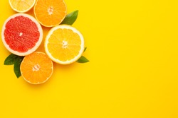Citruses fruits on Illuminating pantone colored  background with copyspace, fruit flatlay, summer minimal compositon with grapefruit, lemon, mandarin and orange, color of year 2021