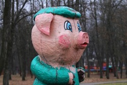 A wooden figure of a fabulous pig in a cap installed in the park.