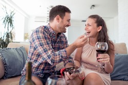 Portrait of young  caucasian eating a heart chocolate cookie.Valentines couple sharing cookie,holds a glass of wine in hands.