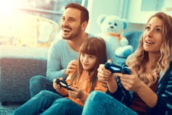 Happy family sitting on a sofa and playing video games.