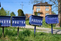 Bright outdoor cluster mail boxes with individual slots in rural Poland. The text in Polish on the mailbox translates to: 'The post office of Poland'                               