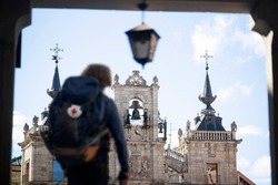 Way of St James , Camino de Santiago , pilgrim unfocused walking  to Compostela  with backpack on central square of Astorga city , Leon, Spain