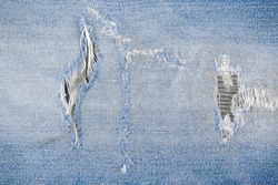 Patch tear Denim jeans textile texture surface for background or wallpaper with copy space. Close up of torn blue jeans fabric pattern design.