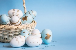 Easter colored eggs in a basket isolated on a trendy blue background. Minimal concept. Card with copy space for text.