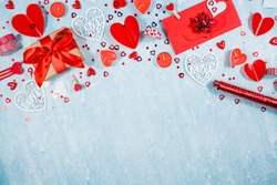 Greeting card for Valentine's Day. Red hearts, gift box, roses and candles on a blue background. Beautiful frame for text. Flatly. Copy the space. The concept of holiday and love.
