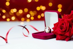 Banner. Gold ring, wedding ring in red box and , red rose on white-red background with beautiful bokeh. The moment of a wedding, anniversary, engagement, or Valentine's Day. Happy day.