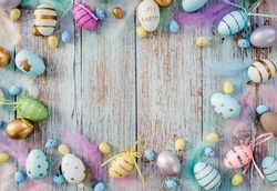 Banner. Easter frame with eggs and feathers on a blue wooden background. The minimal concept. Top view. Card with a copy of the place for the text.