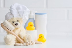 Baby bath accessories, children care, a yellow bear with a towel on its head, a brush and bottles of shampoo.
