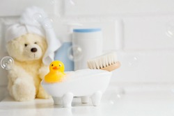 Children's bath accessories. Baby care. Bear with a towel on his head, a brush and bottles of shampoo. A miniature bubble bath and a yellow rubber duckling for bathing.