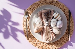Banner. Table setting. A plate with a rabbit on a napkin, lavender and Easter eggs on a fashionable background of 2022 is a veri pery. Top view. The concept of a happy Easter holiday for cafes and res
