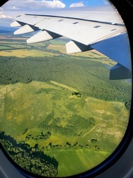 View of the Ground and the wing of the aircraft from the window of the aircraft. Russia, takeoff from Domodedovo airport. A beautiful landscape with a forest from the airplane window.