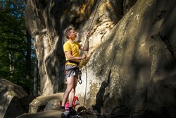 The climber belays the partner. A rock climber climbs a rock. The climber trains on natural terrain. A man trains strength and endurance.  Active lifestyle. Extreme sports. Rock climbing in Carpath.