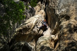 A female teen rock climber climbs a rock. The climber trains on natural terrain. A teenager trains strength and endurance.  Active lifestyle. Extreme sports. Rock climbing in Carpath.