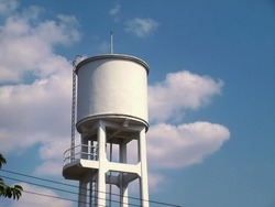 White concrete water tank on the tower. large outdoor public water storage tanks for water supply in villages or communities in the city On the sky background with copy space.