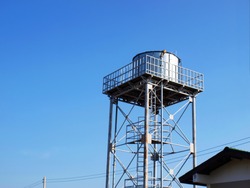 Silver water tank on the tower On a clean blue sky background With copy space