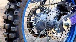 Brake system and rear wheel hub motocross motorcycle. Blue rims with tires and spokes. Select the content and focus.