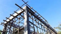 Concrete pillars and crutches. Structure of the house with concrete cantilever beams in the bottom view against a bright blue sky background. selective focus