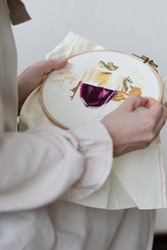 Cross-stitch embroidering in progress. Young girl in linen clothes is doing handmade embroidery. High quality photo