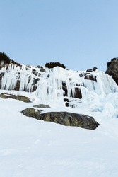 Frozen waterfall Skok in High Tatras (Slovakia) in winter time. Big waterfall with blue giant icicles frost on the rocks.