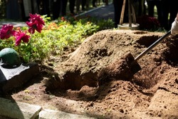 Burying grave. Funeral details. Mourning ceremony. Gravedigger with shovel. Burial of body.